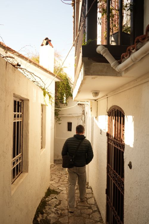 Free A person walks down a narrow, sunlit alley in Marmaris, Türkiye, showcasing rustic architecture. Stock Photo