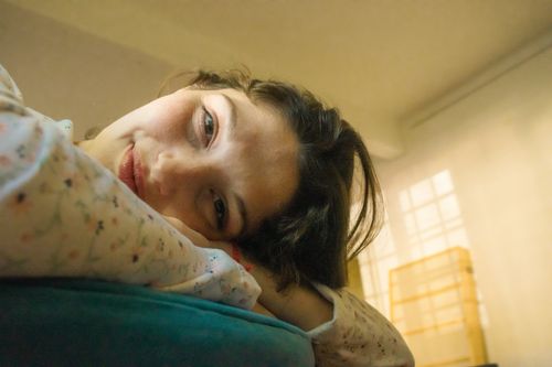 Free A woman peacefully lying on a cushion indoors, with a soft and cozy atmosphere. Stock Photo