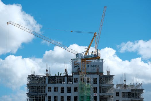 Cranes at a construction site for a high-rise building under a bright blue sky in Central Visayas, Philippines.