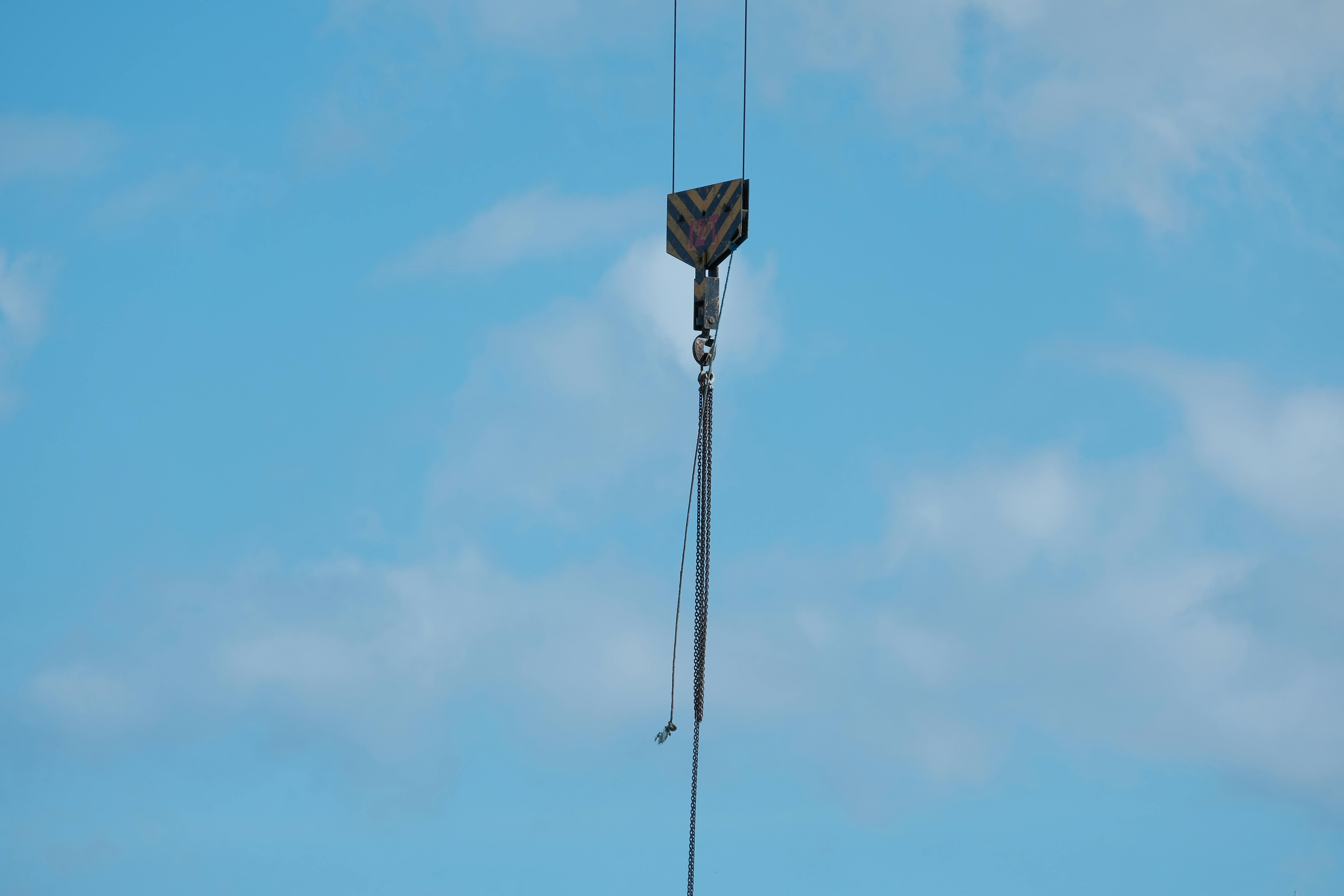 Gratis Una vista detallada de un gancho de grúa suspendido contra un cielo azul brillante, que ilustra temas industriales. Foto de stock