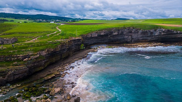 Explore the breathtaking coastal cliffs and vibrant ocean of Galicia, Spain, captured in a vivid aerial view.