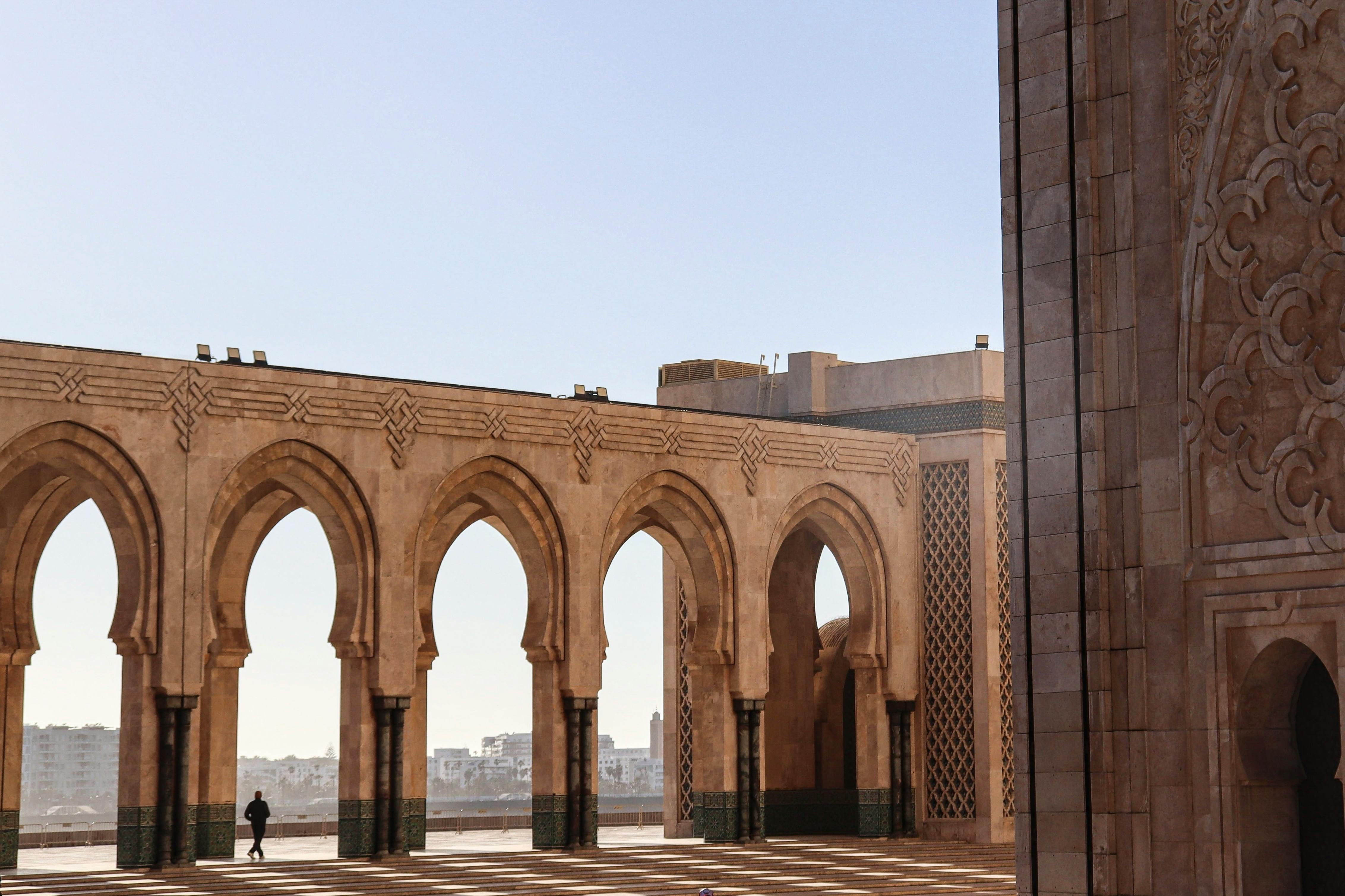 бесплатная Утренний свет отбрасывает тени на величественные арки мечети Хасана II в Касабланке. Стоковое фото