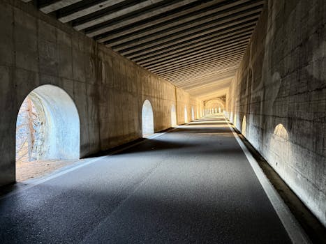Serene view of a long concrete tunnel with natural light filtering through arched openings.