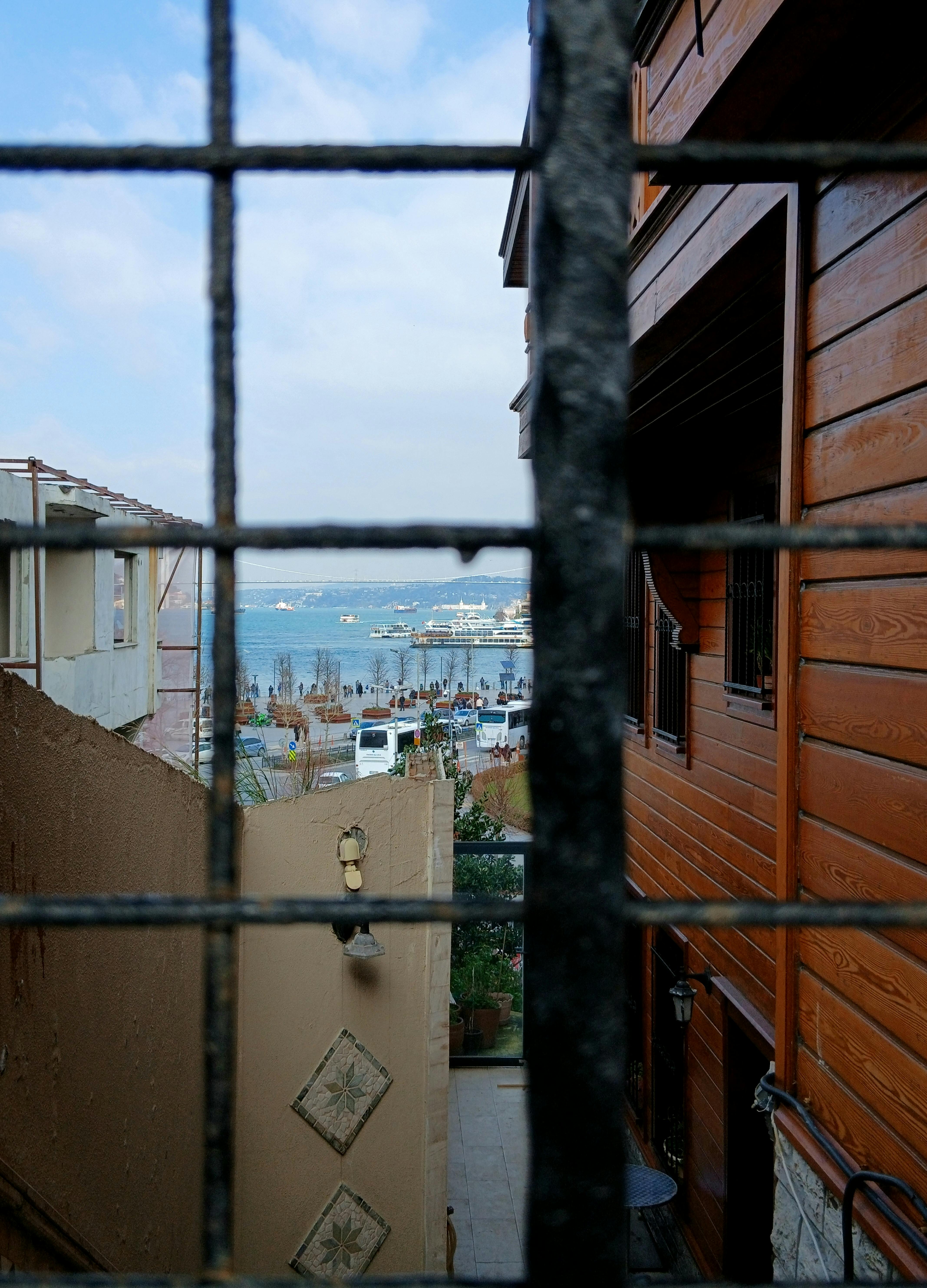 無料 都会の路地と金属製のフェンスに囲まれた美しい海辺の景色。穏やかな海岸の雰囲気が漂います。 写真素材