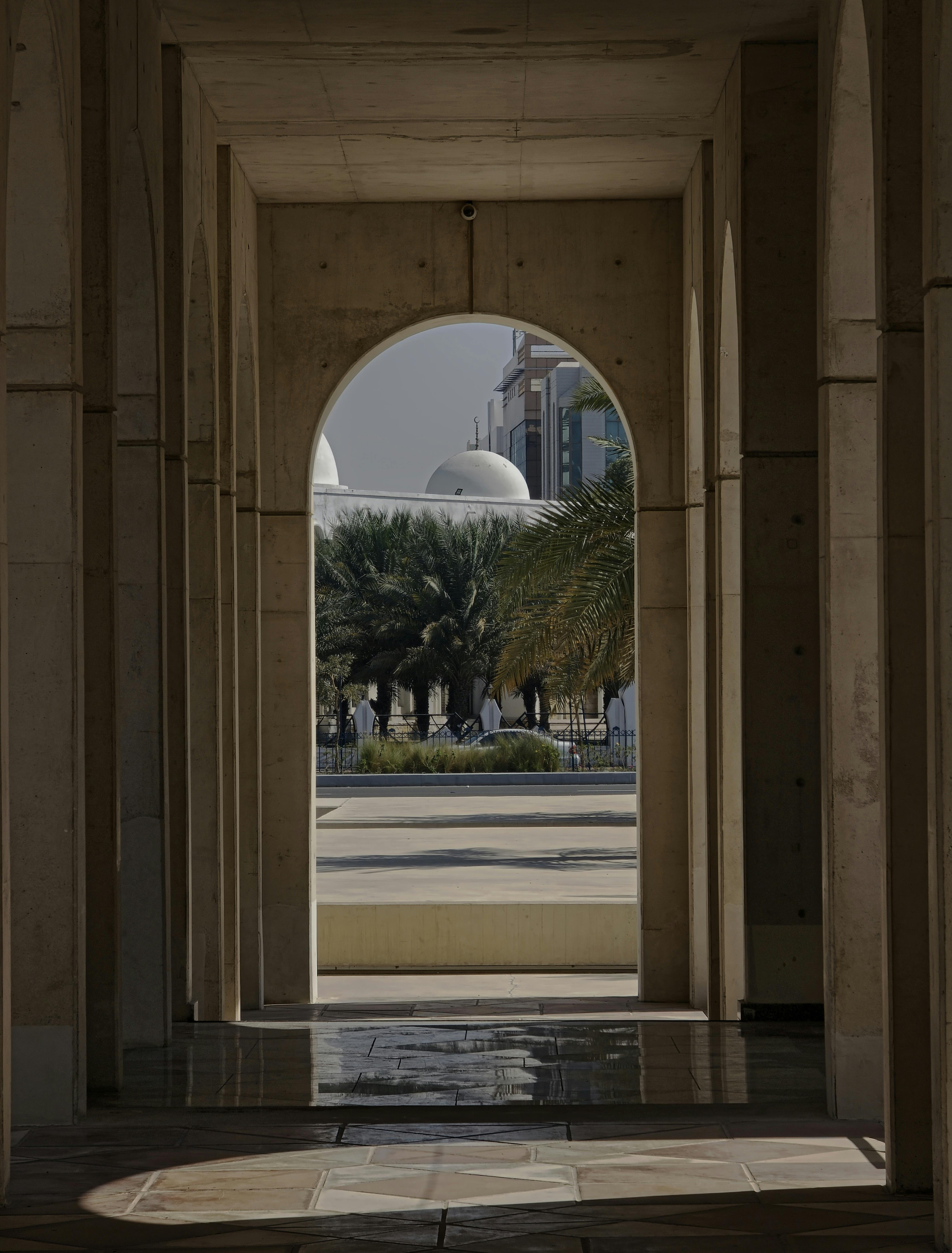 無料 アブダビの現代建築と伝統建築の融合を示すアーチ越しの魅惑的な眺め。 写真素材