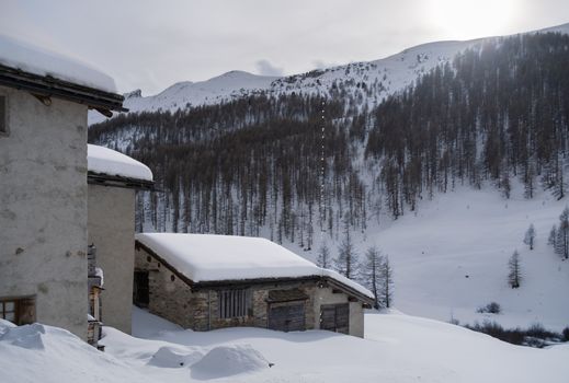 Serene winter scene with snow-covered cabins in a mountainous Alpine landscape.