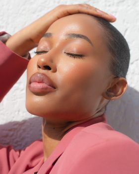 Close-up portrait of a woman basking in sunlight wearing a pink jacket in Lagos.