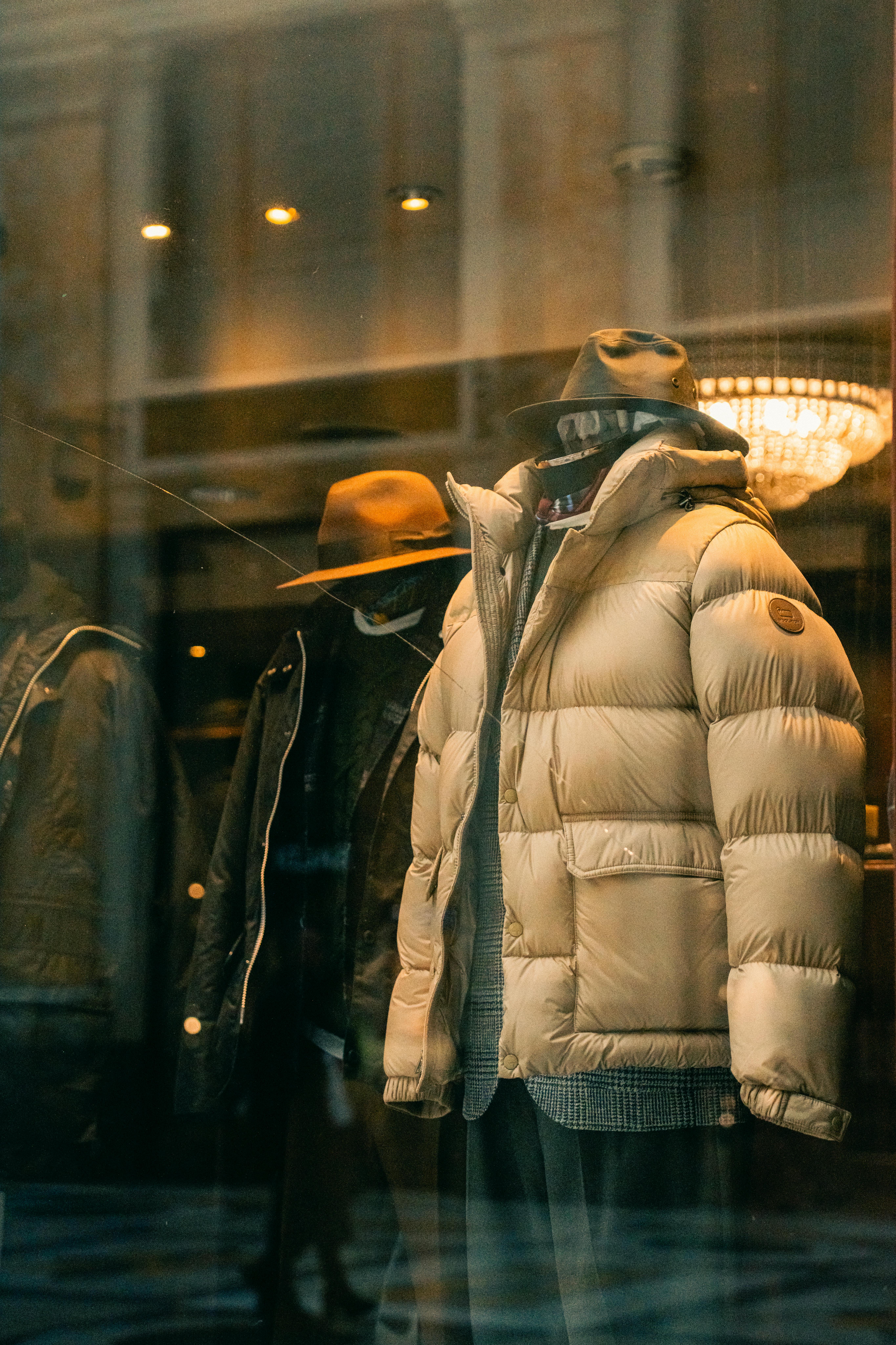 бесплатная Манекен в бутике в Неаполе демонстрирует зимнюю куртку и шапку при теплом освещении. Стоковое фото