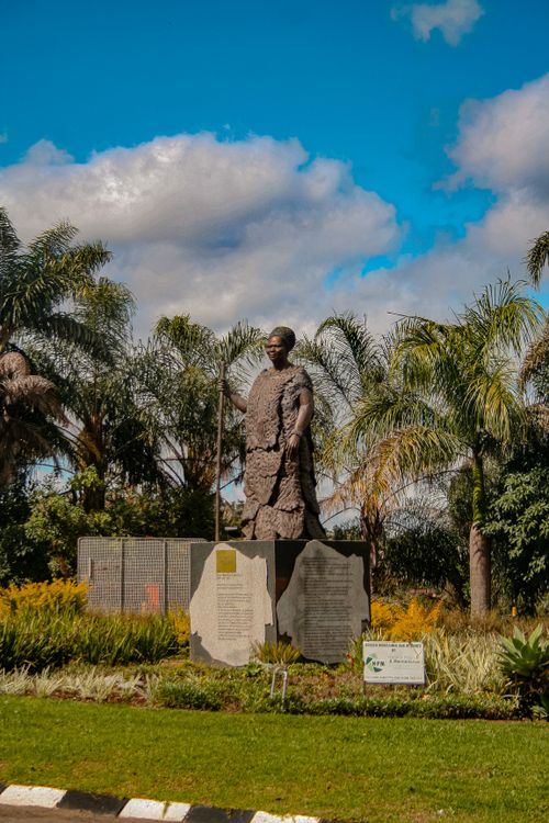 Free Memorial statue amidst palm trees and a vibrant sky in a peaceful outdoor setting. Stock Photo