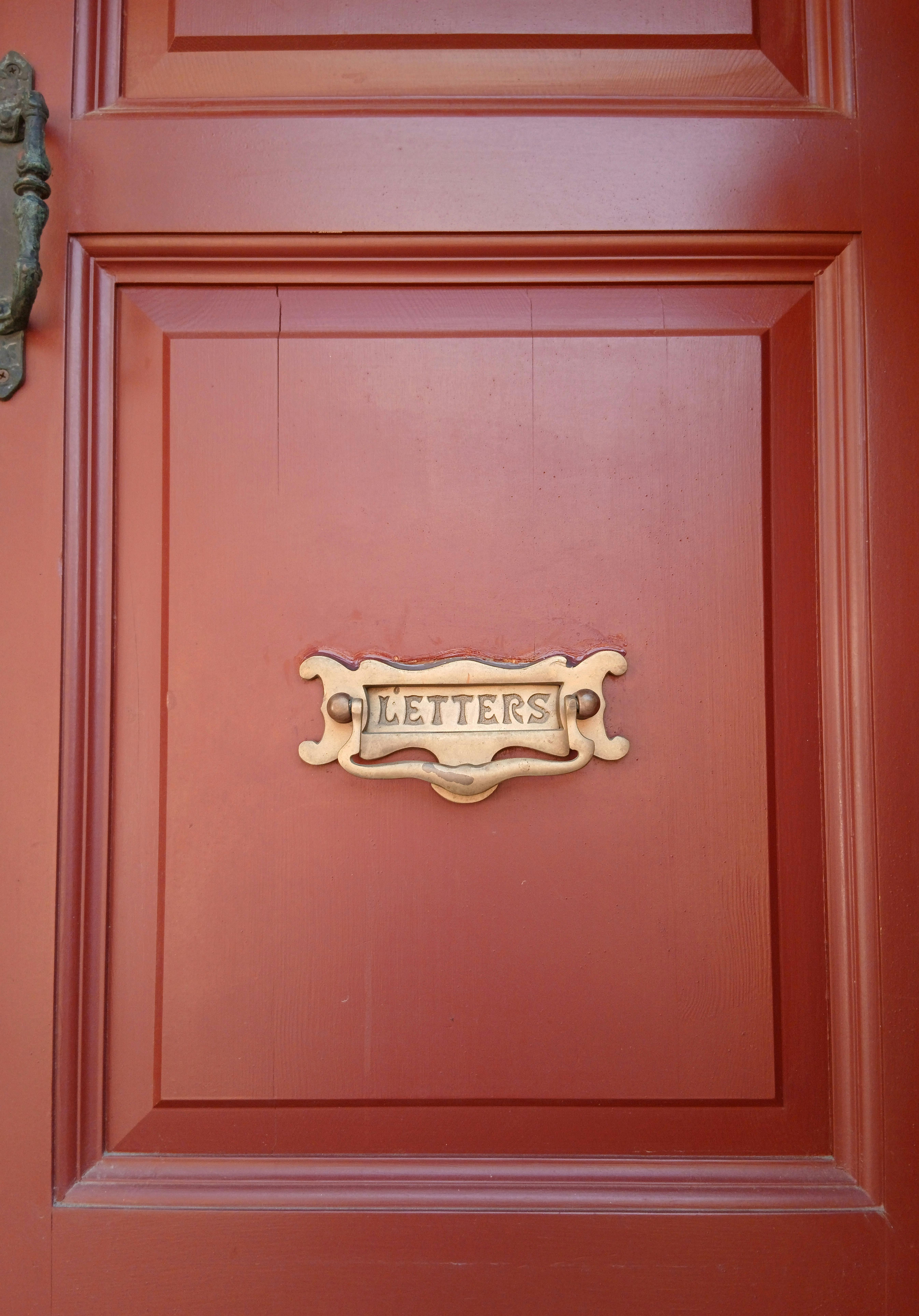 無料 複雑なデザインのビンテージ レター スロットを備えた赤い木製のドア。 写真素材