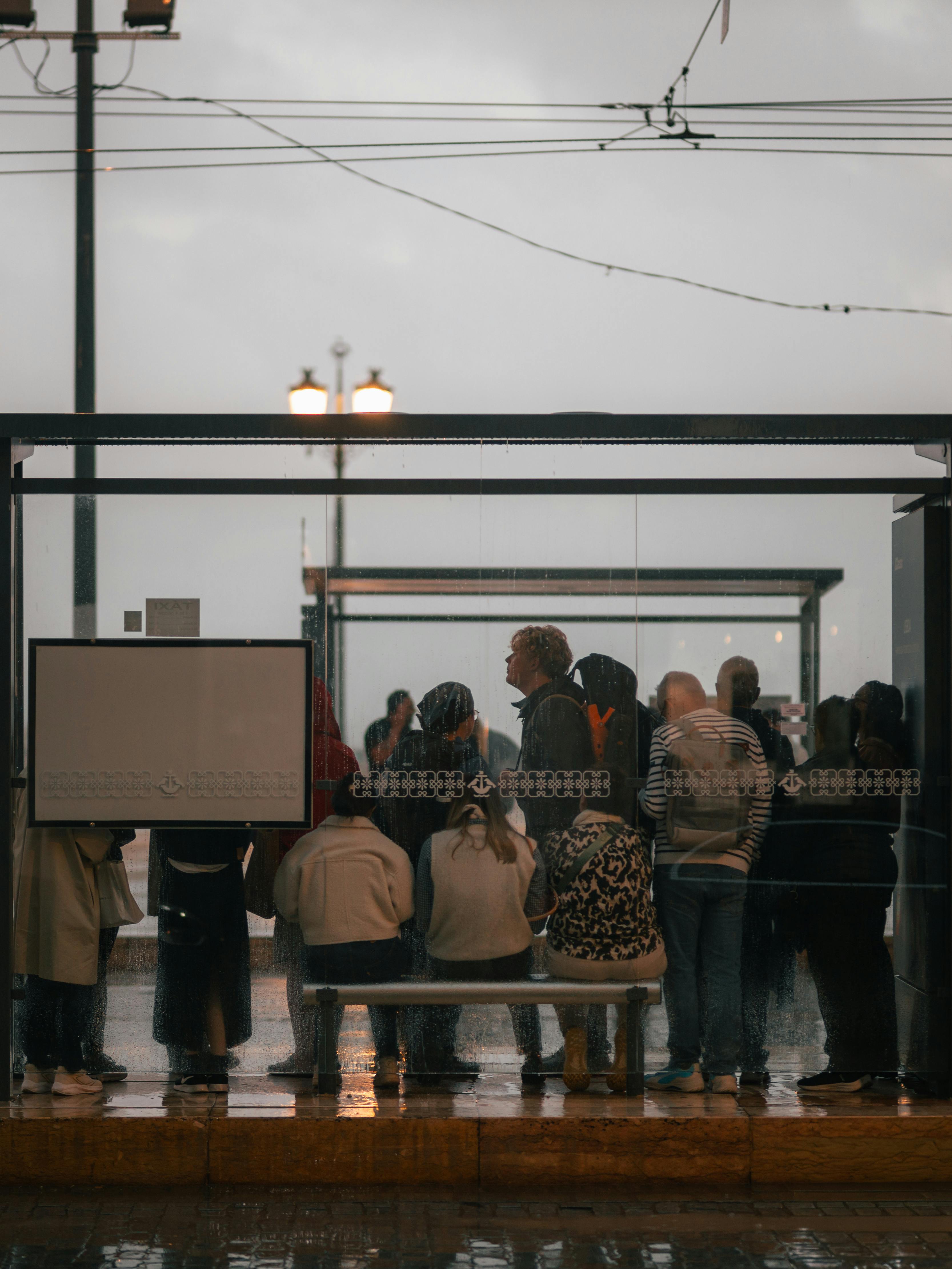 Free People waiting at a bus stop during a rainy day, captured from behind the glass. Stock Photo