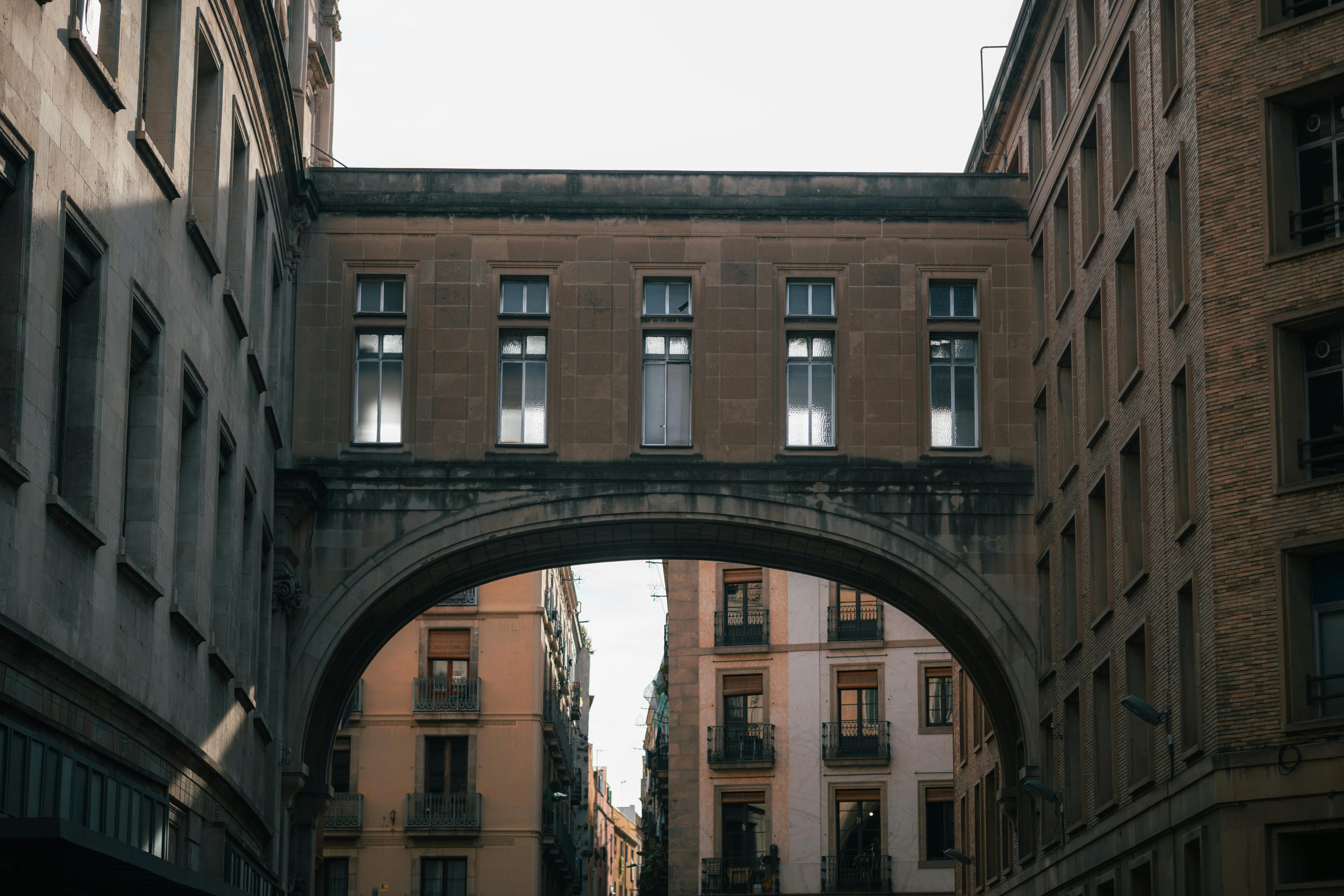 無料 建物を結ぶアーチ橋のある歴史的な街の通りを撮影した写真です。 写真素材