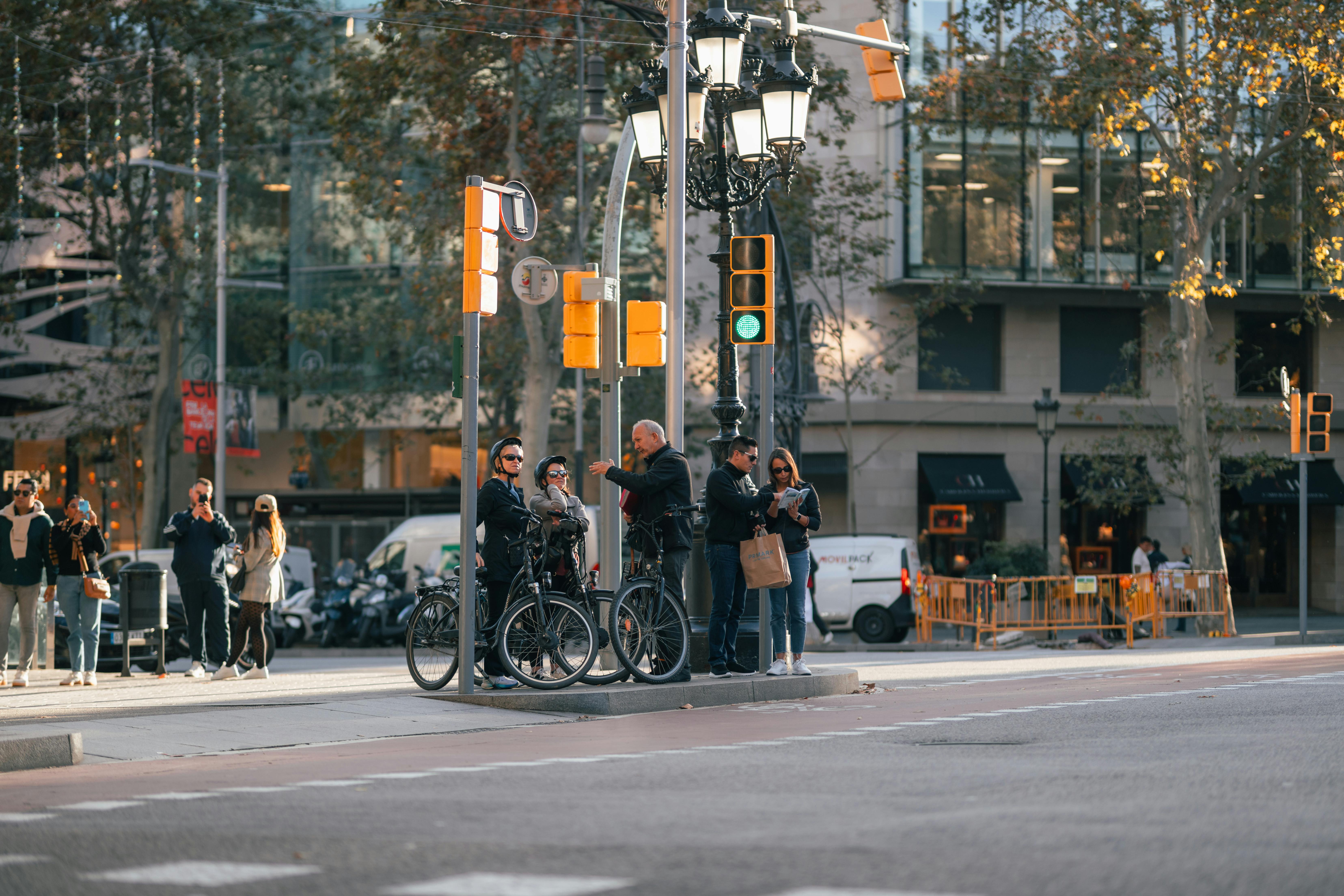 無料 信号待ちをしている自転車や歩行者がいる活気のある街の交差点。 写真素材
