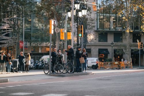 Free A lively city street intersection with cyclists and pedestrians waiting at the traffic light. Stock Photo