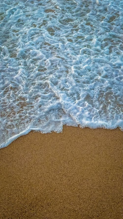 Free Waves gently lap against the sandy shore in Alexandria, Egypt, capturing the serene beauty of the coastline. Stock Photo