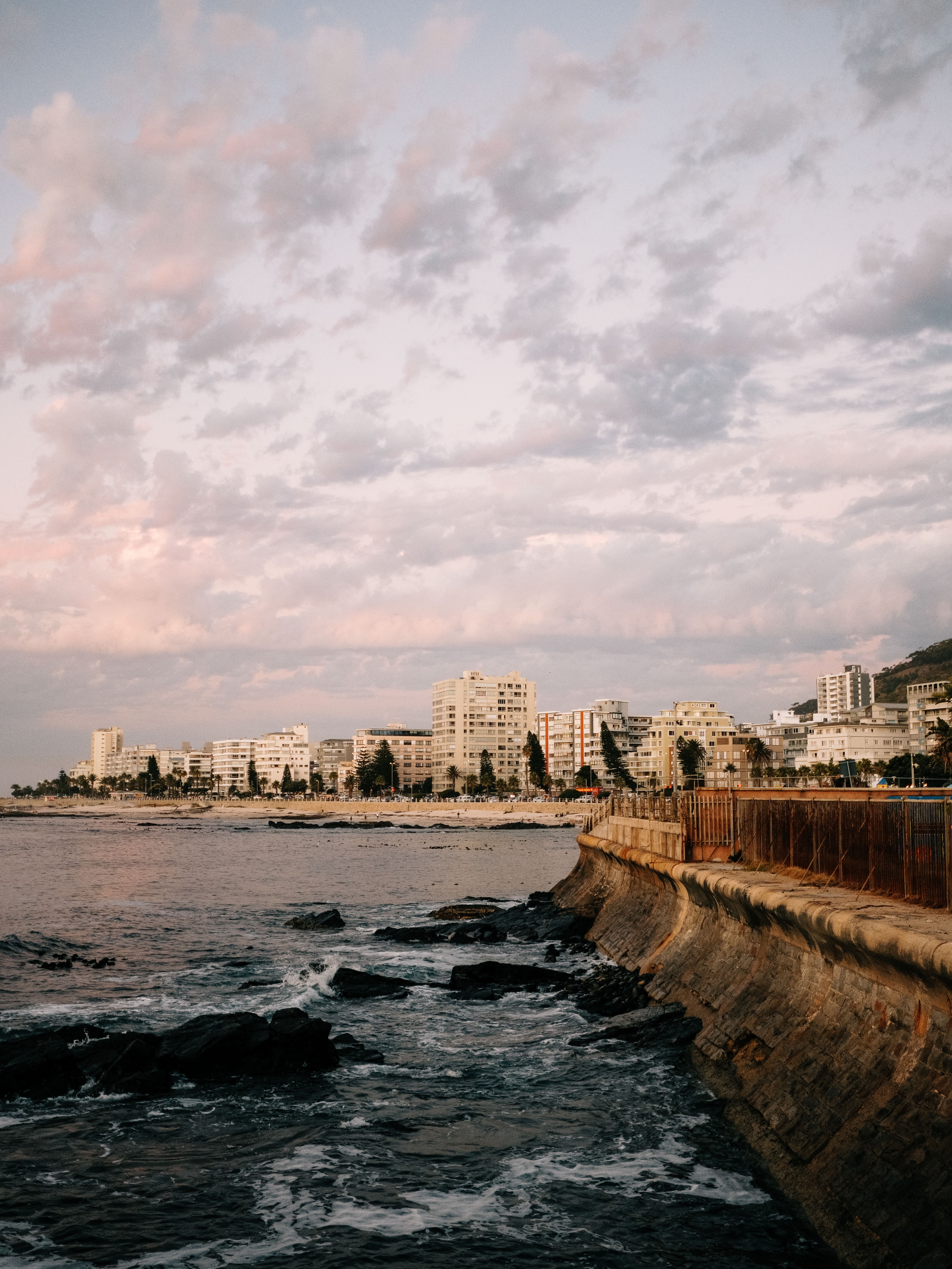 Elegant view of Cape Town's coastline and buildings under a pastel sunset sky.