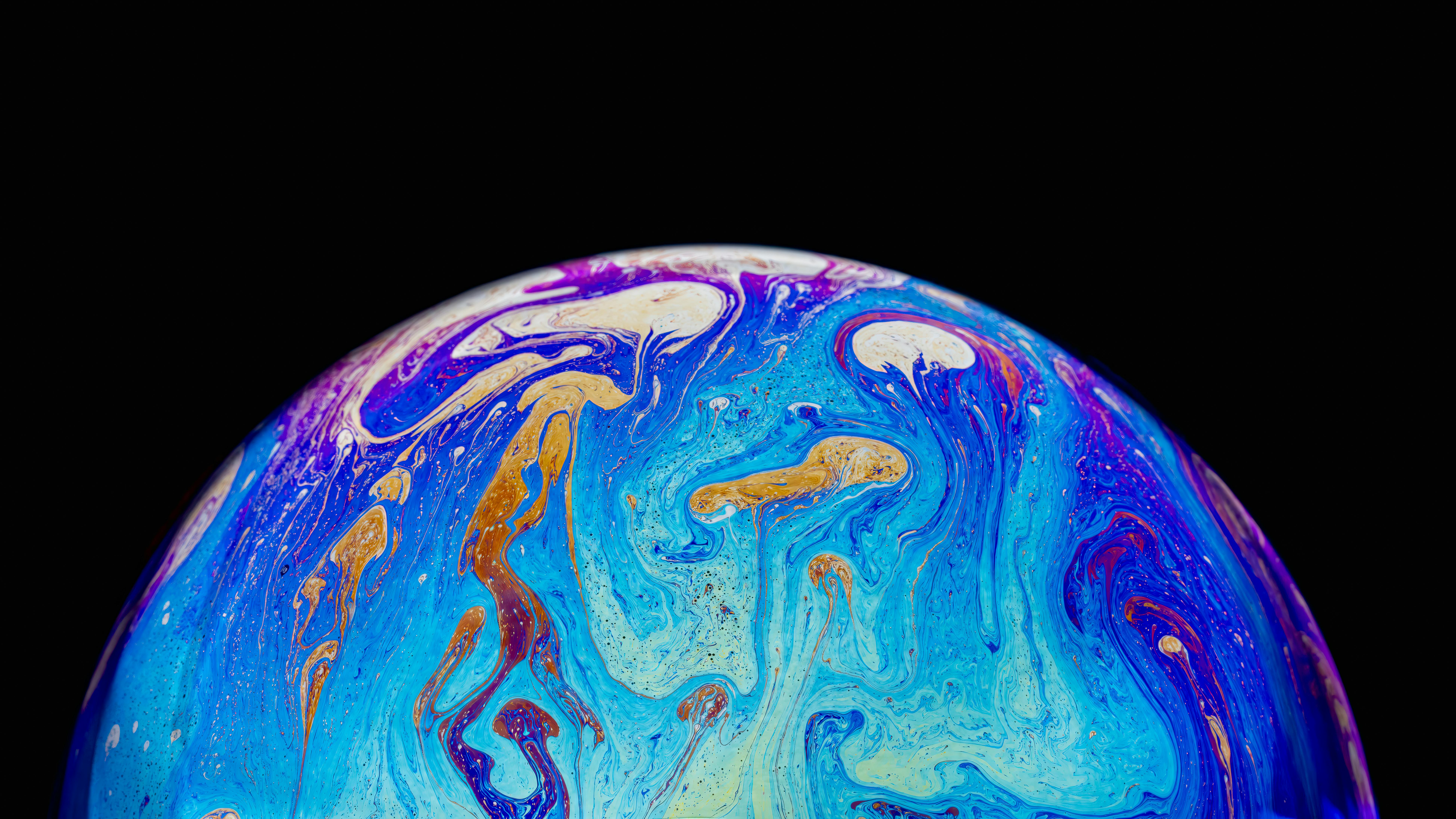 Free Stunning close-up of vibrant soap bubble with swirling iridescent colors against a black background. Stock Photo