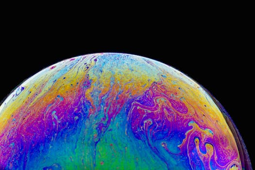 Colorful abstract close-up of a soap bubble with iridescent patterns on a black background.