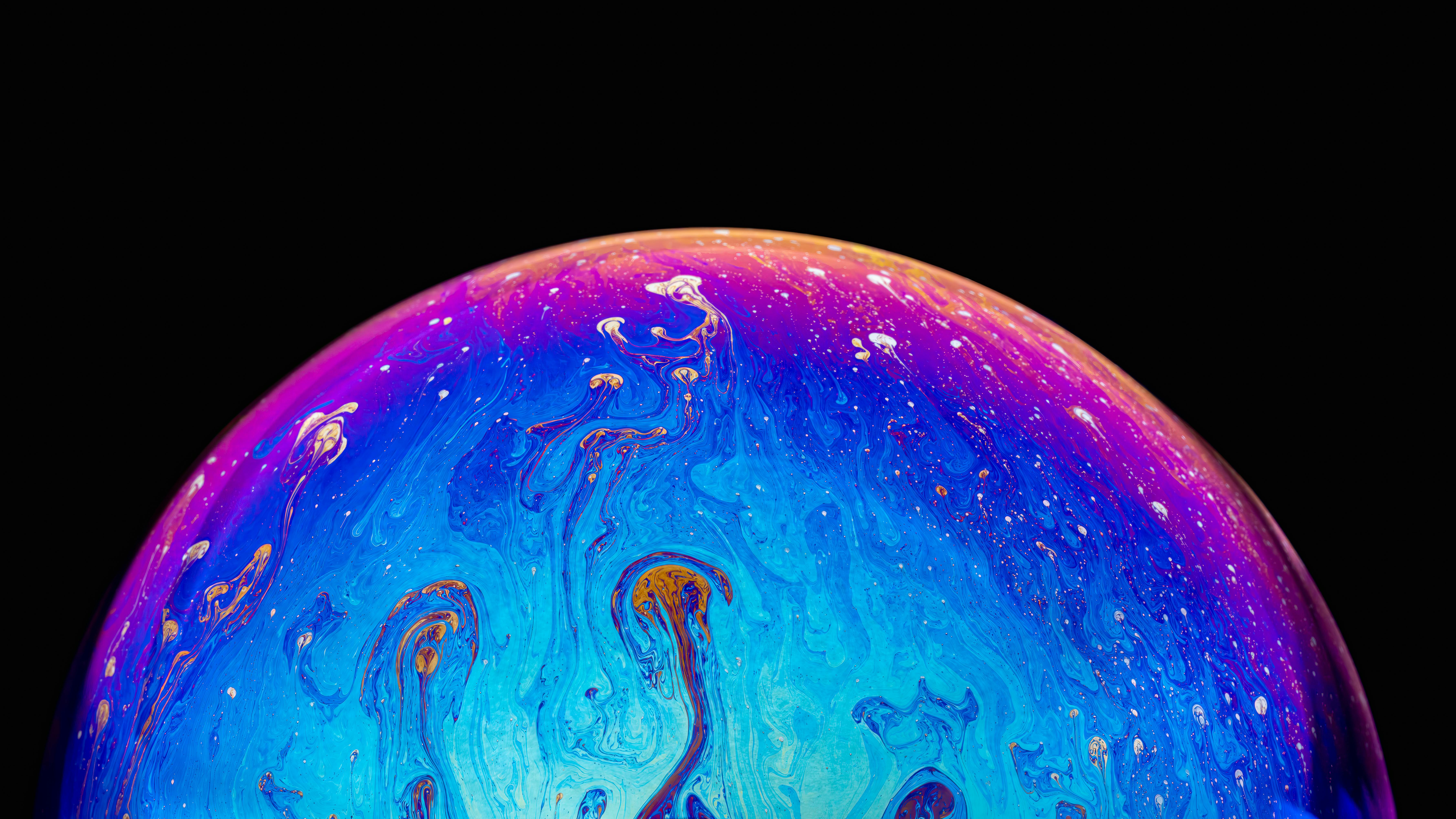 Free Colorful macro shot of an iridescent soap bubble creating abstract patterns against a black background. Stock Photo