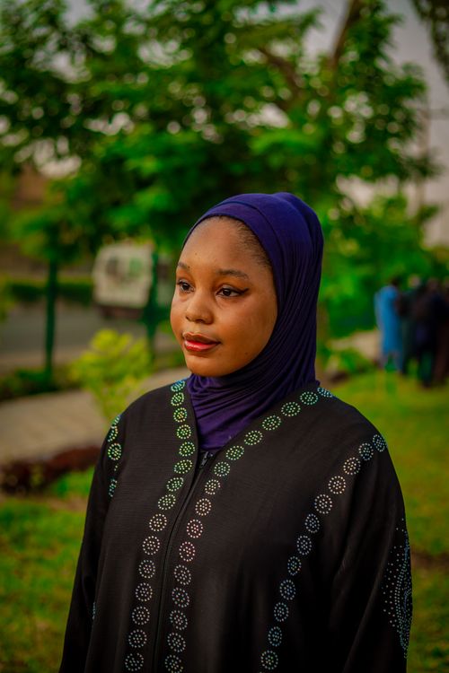 Free A young woman in traditional attire poses gracefully outdoors with lush green background. Stock Photo