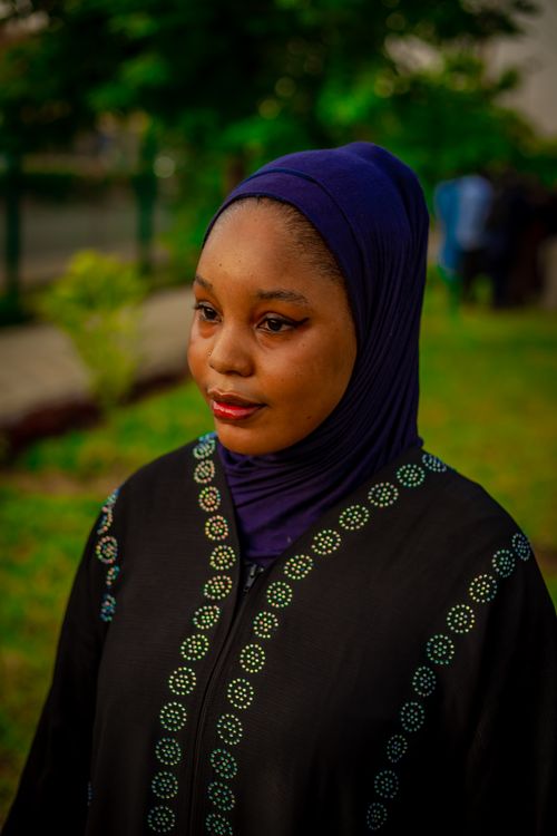 Free A thoughtful woman in a black abaya and purple hijab stands outdoors on a lush green day. Stock Photo