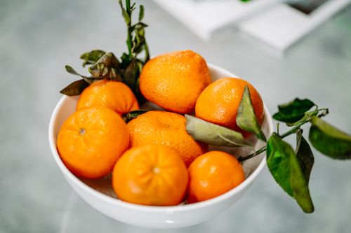 Free A bowl of fresh oranges with green leaves creating a vibrant and healthy kitchen decor. Stock Photo