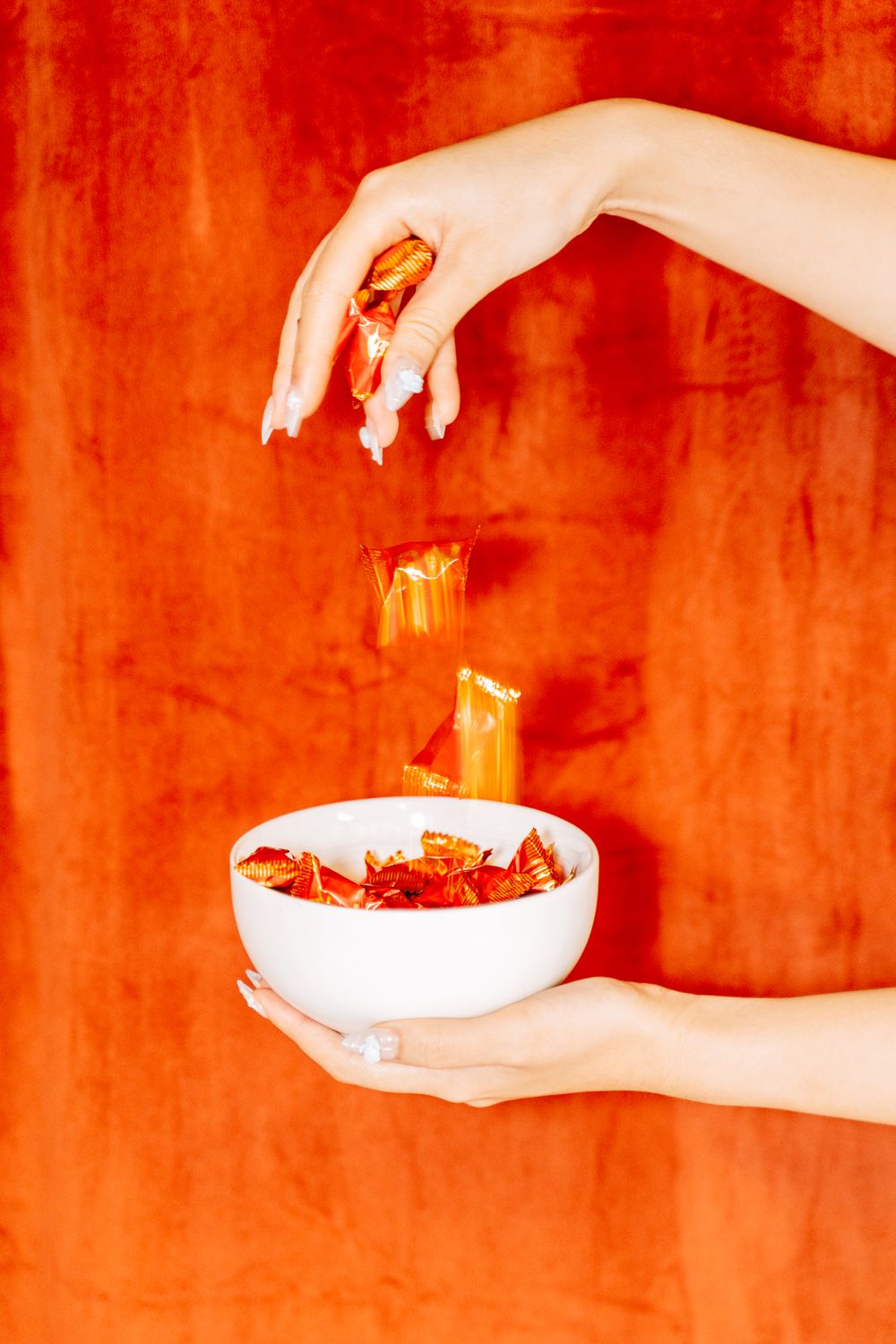 Hands pouring colorful wrapped candy into a bowl at Zingx Home candy store