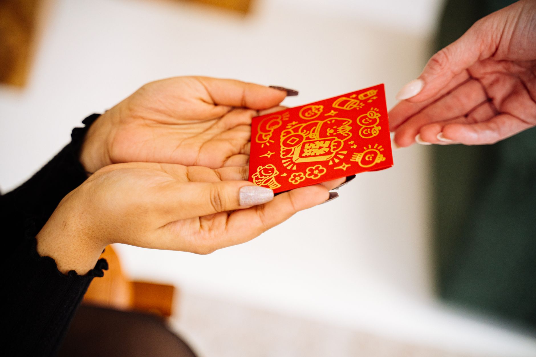 Close-up of hands exchanging a red envelope, symbolizing traditional Lunar New Year gift giving.