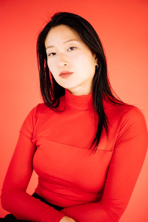 Free Asian woman in red blouse, posing indoors against vivid background for a studio portrait Stock Photo