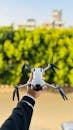 Hand Holding Drone Against Lush Green Background