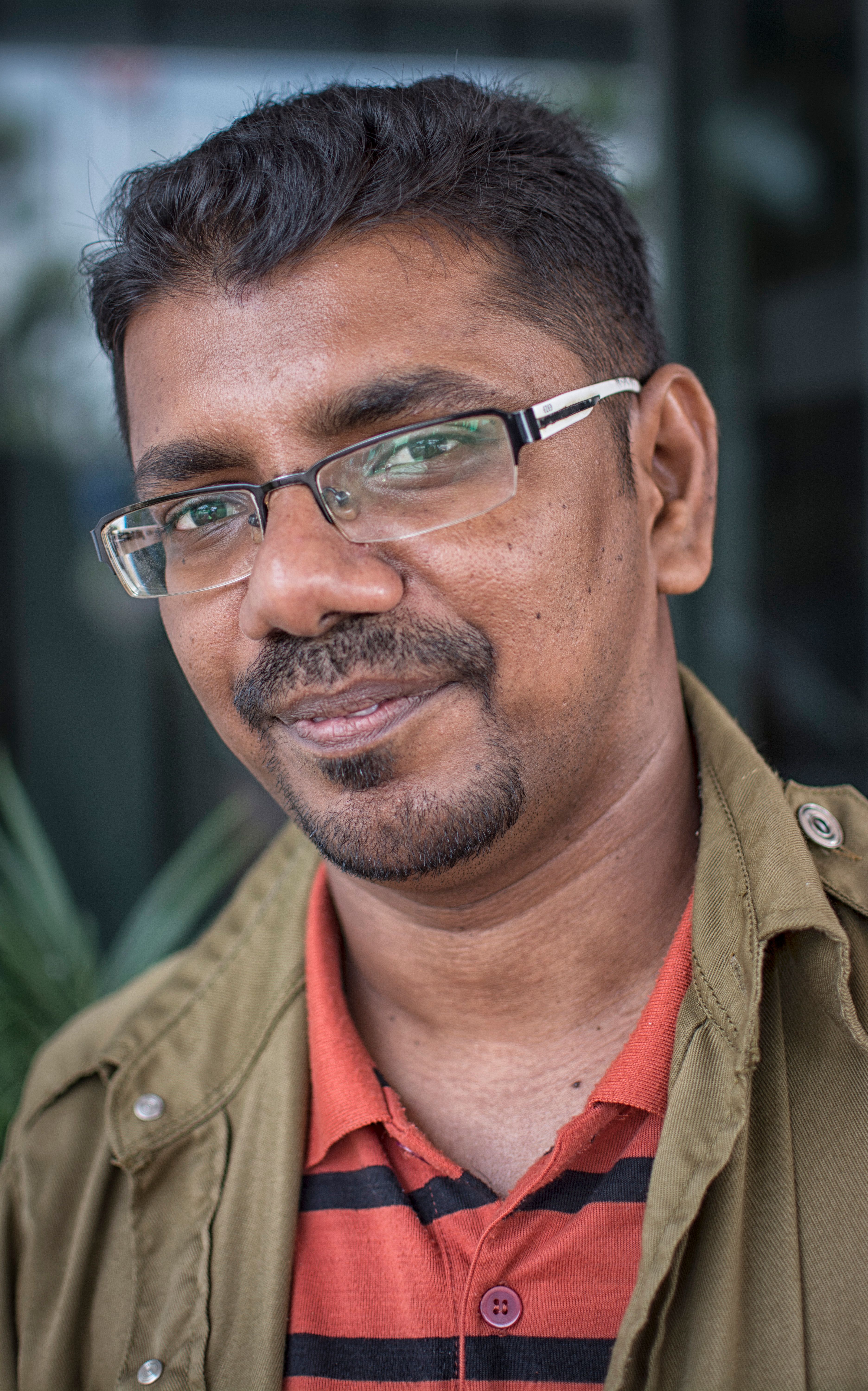 Smiling man in his thirties wearing glasses, outdoors.