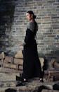 Elegant Woman in Black Dress by Brick Wall