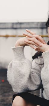 Aesthetic close-up of a woman in a cozy sweater showcasing delicate hand gestures outdoors.