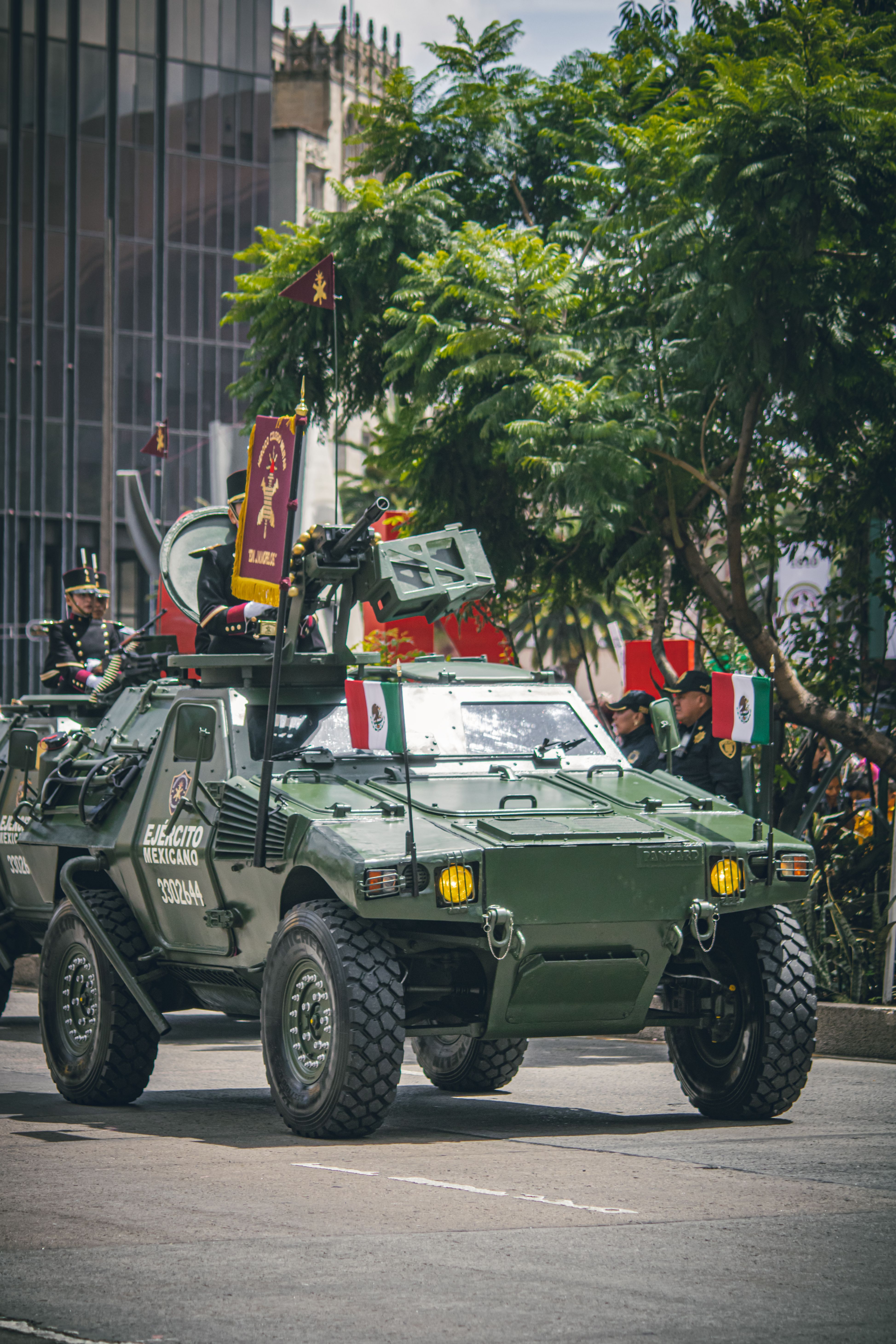 Mexican military parade featuring a green armored vehicle adorned with flags and decorations in Mexico City.