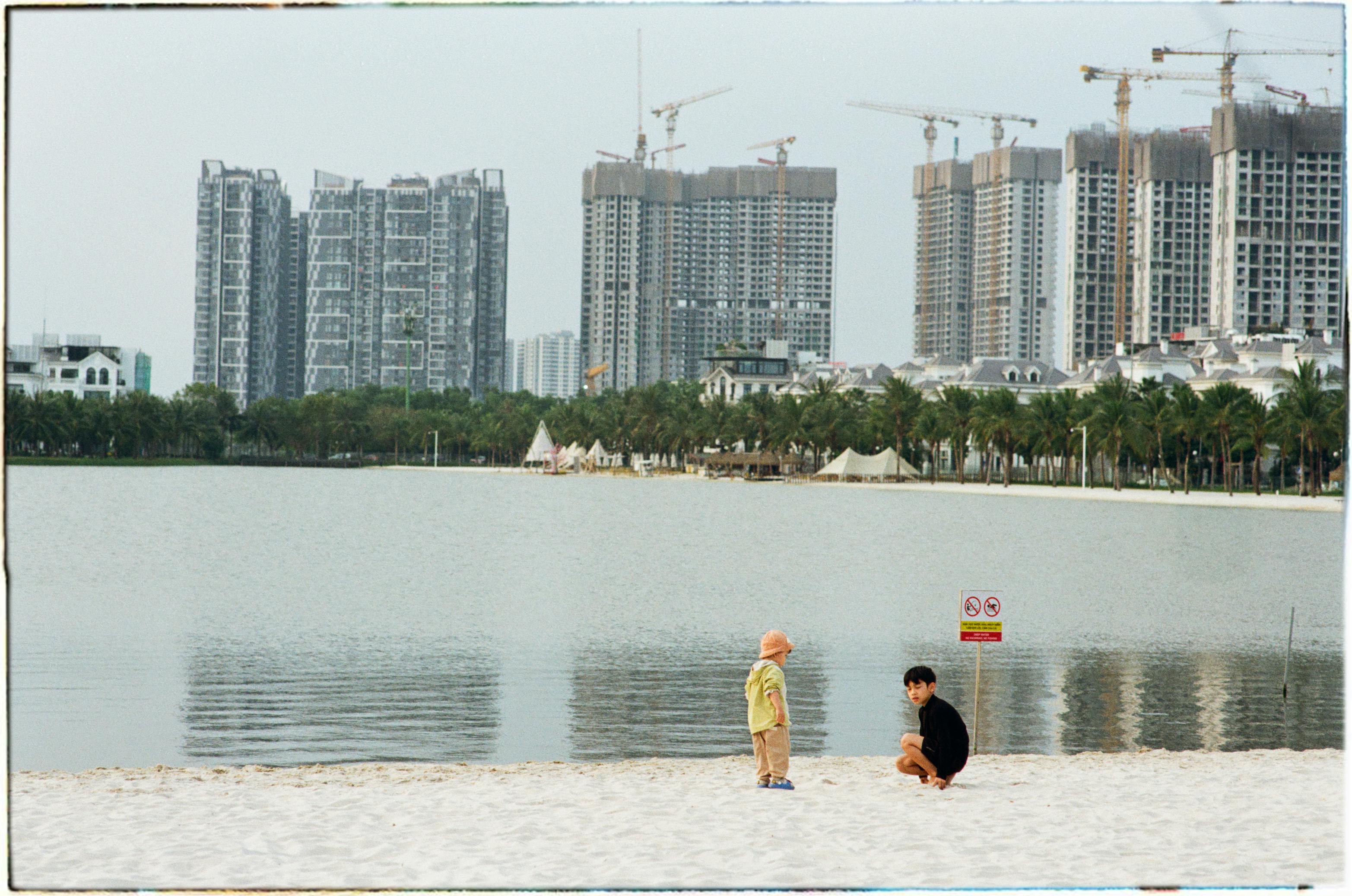 бесплатная Дети играют на пляже у озера на фоне городского пейзажа в Ханое, Вьетнам. Стоковое фото