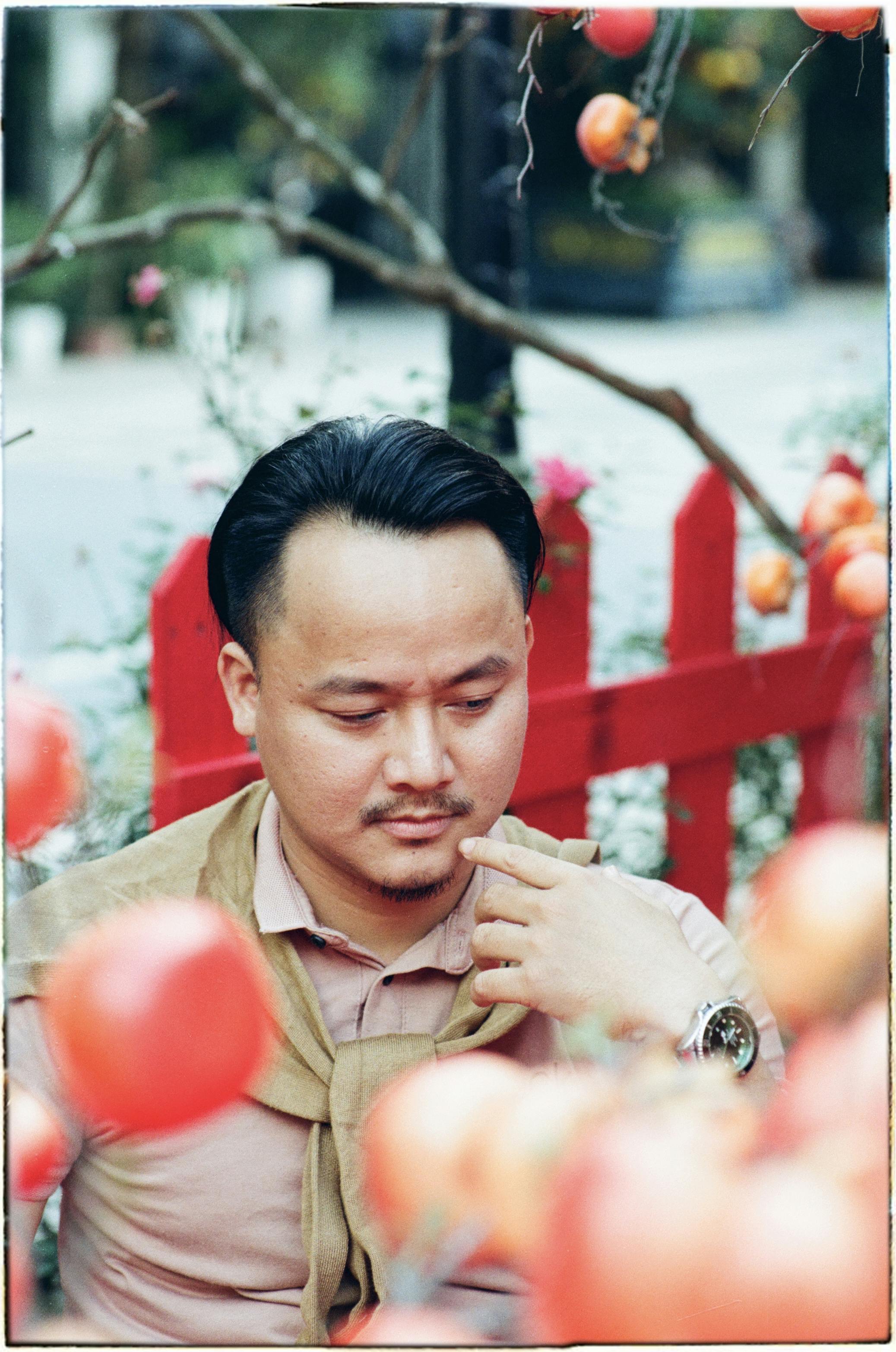 бесплатная Портрет задумчивого мужчины в уличном вьетнамском кафе в окружении красочного декора. Стоковое фото