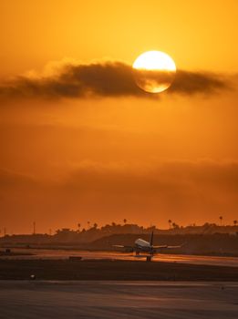 Captivating image of an airplane landing at LAX as the sun sets, painting the sky in warm hues.