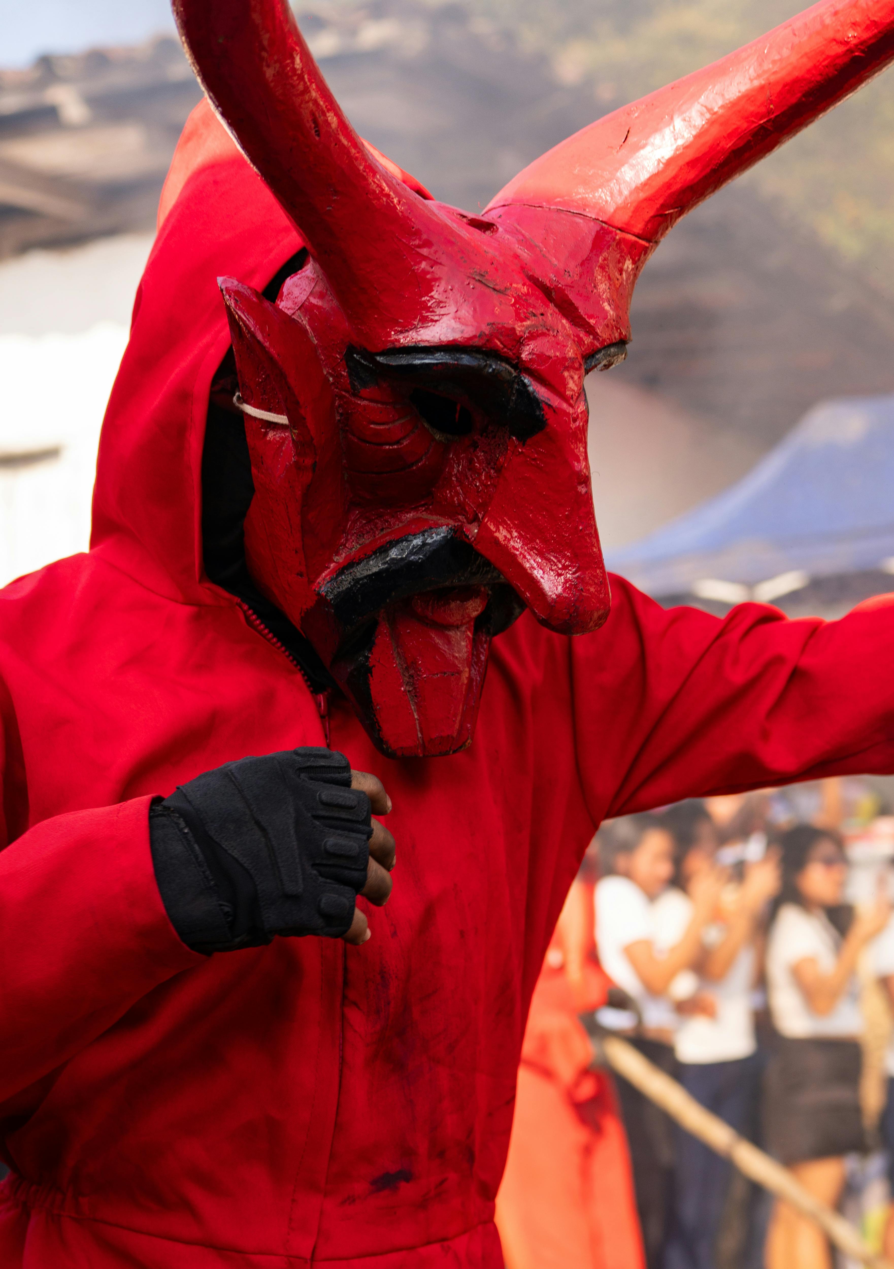 Gratuit Une silhouette vêtue d'un costume rouge éclatant lors d'un carnaval à Tlapehuala, Puebla, mettant en valeur la culture et les festivités traditionnelles. Photos