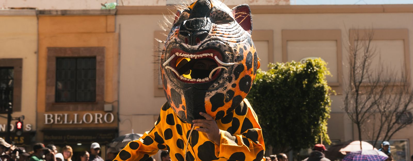 Vibrant festival parade in Pachuca with a performer in a jaguar mask, surrounded by crowds.