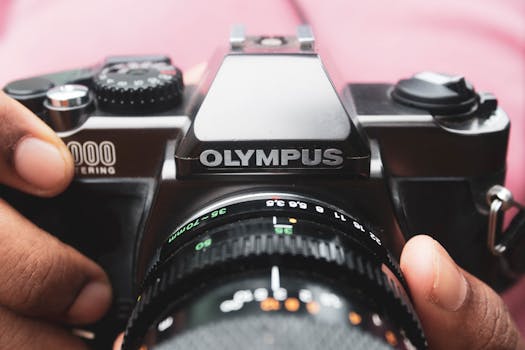 手持经典奥林巴斯相机，镜头对焦清晰