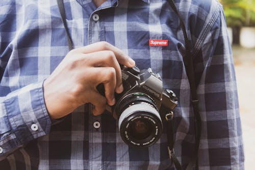 Man Wearing Purple Plaid Shirt Holding Camera