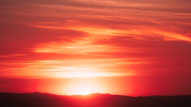 A breathtaking scene of a vibrant sunset casting warm hues over distant mountains.