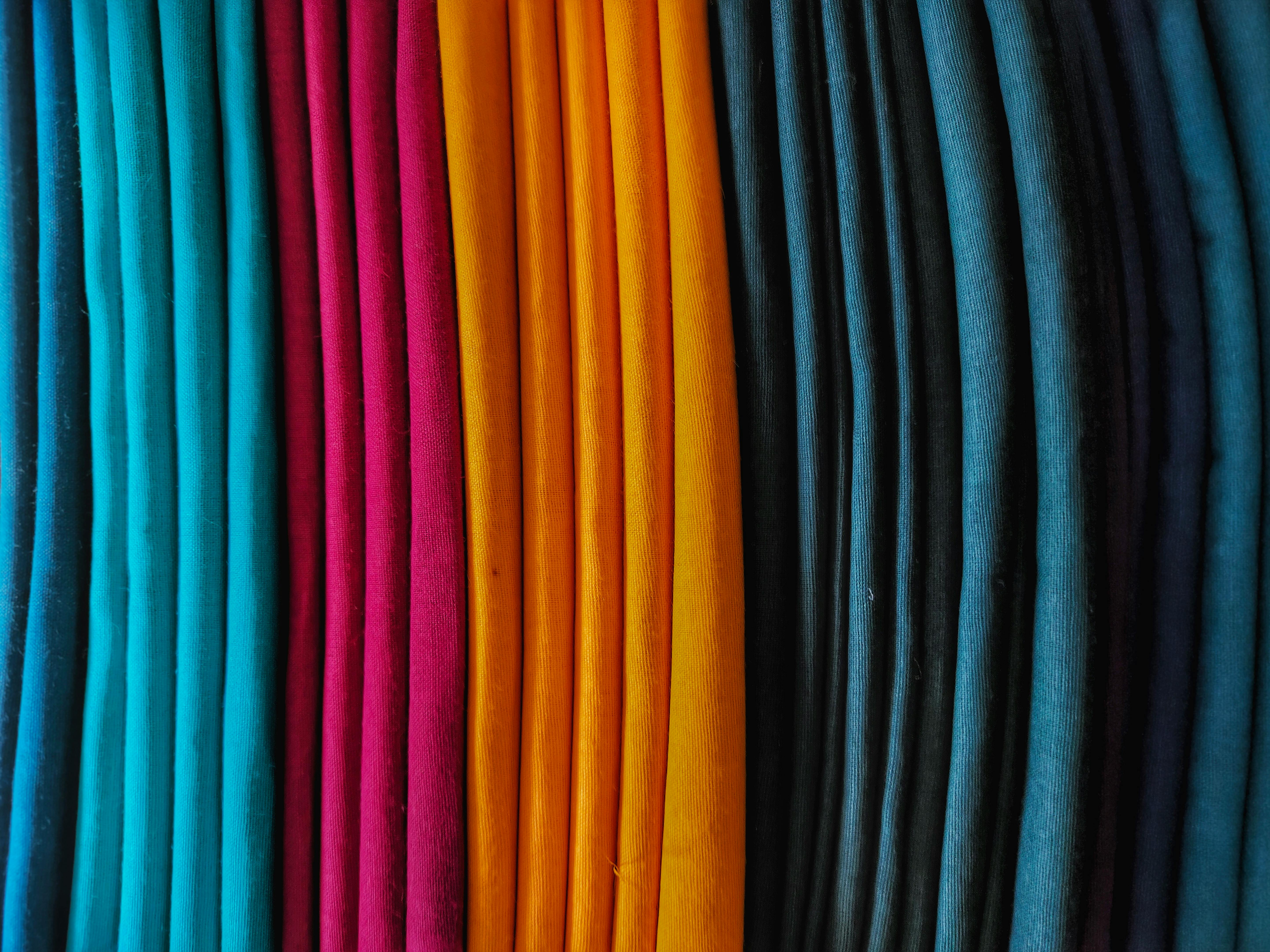 Ücretsiz Canlı renklerdeki kumaş ruloları düzgün bir şekilde üst üste istiflenmiş, göz alıcı renk ve dokuları sergiliyor. Stok Fotoğraflar