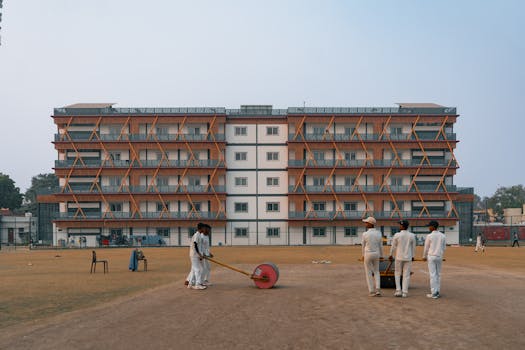 Young cricketers prepare the field in front of a building in Delhi, India.