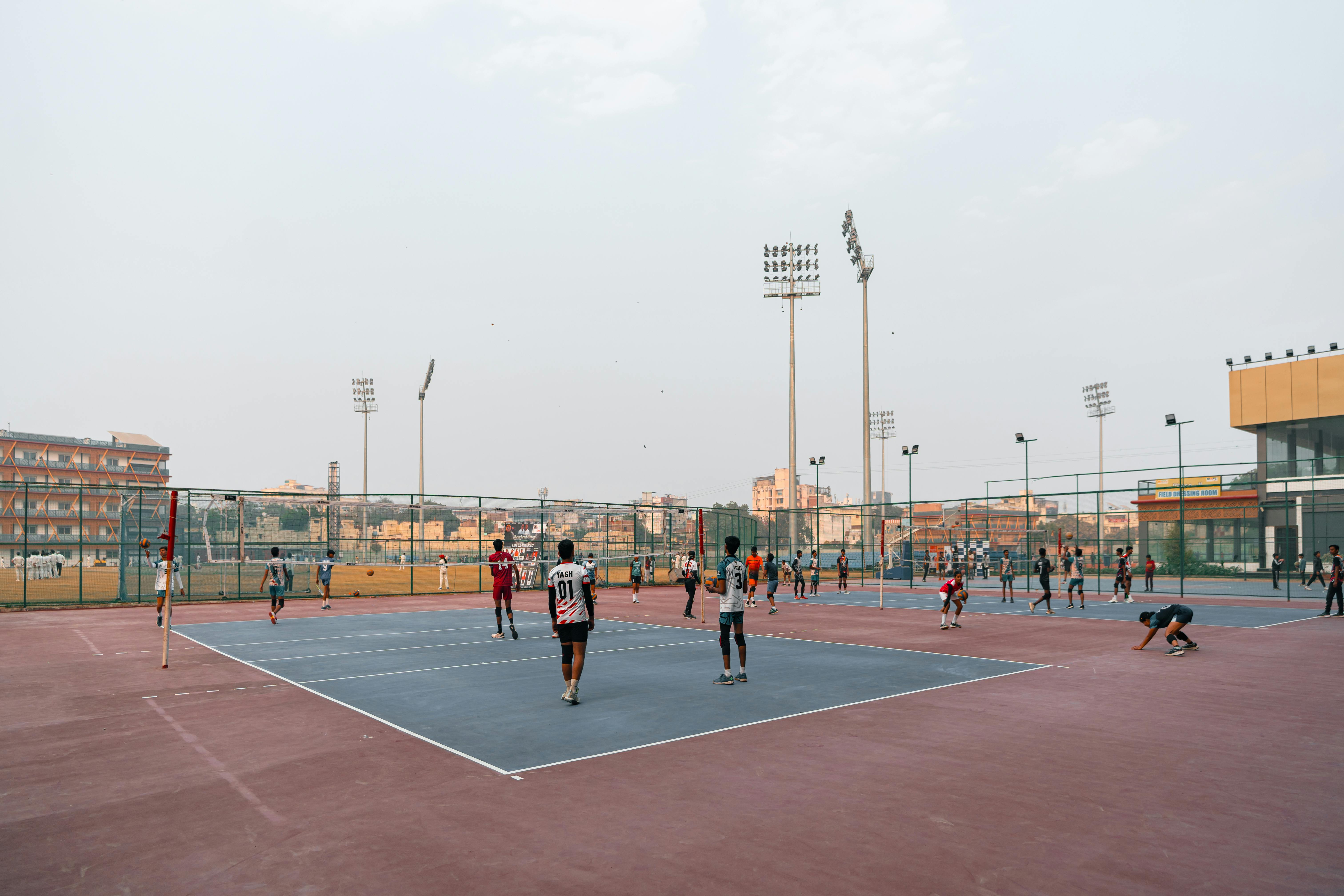 бесплатная Игроки участвуют в волейбольном матче на открытой площадке в городском пейзаже. Стоковое фото