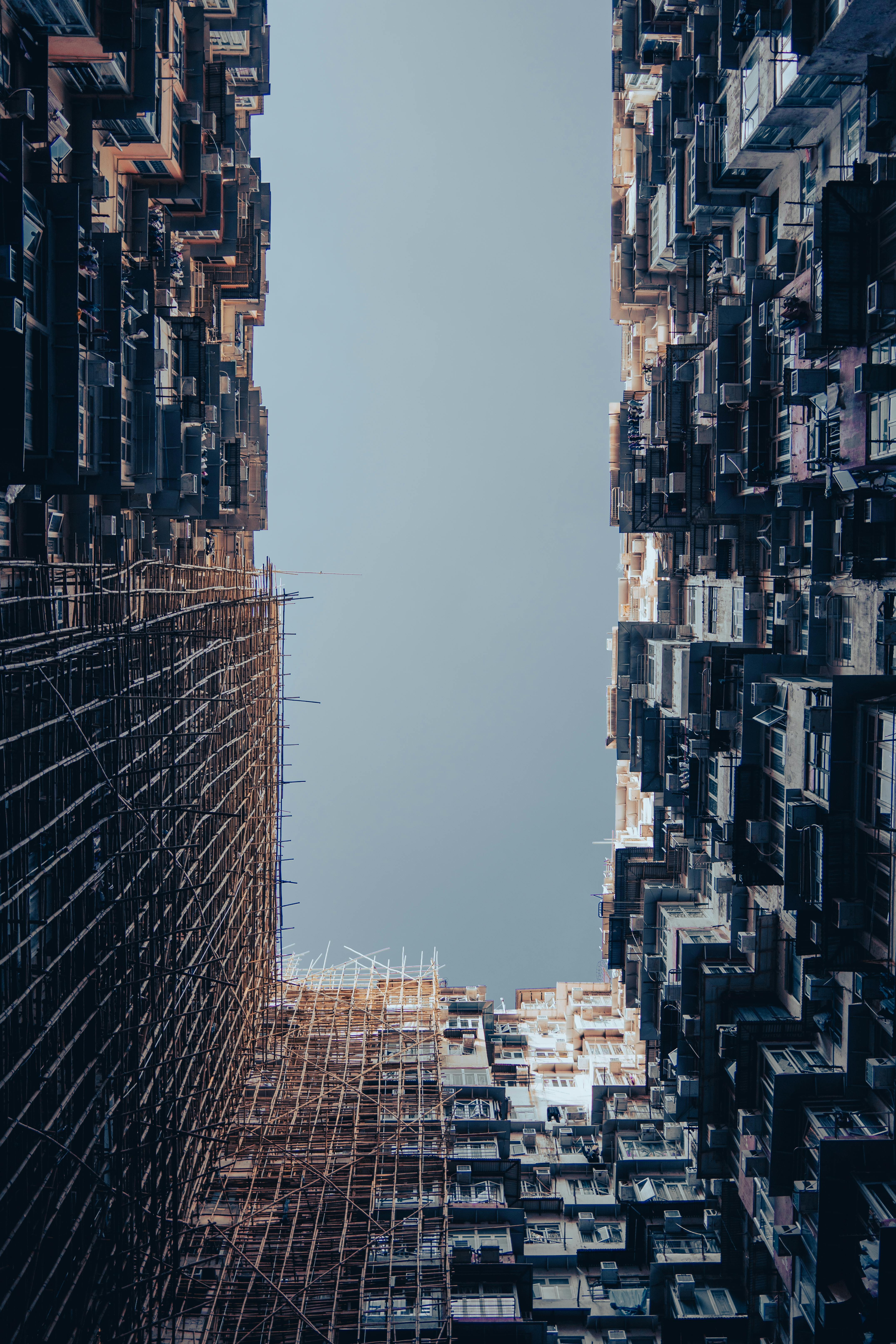 無料 澄んだ空の下、竹の足場が組まれた密集した住宅ビルの眺め。都市建築の代表例です。 写真素材