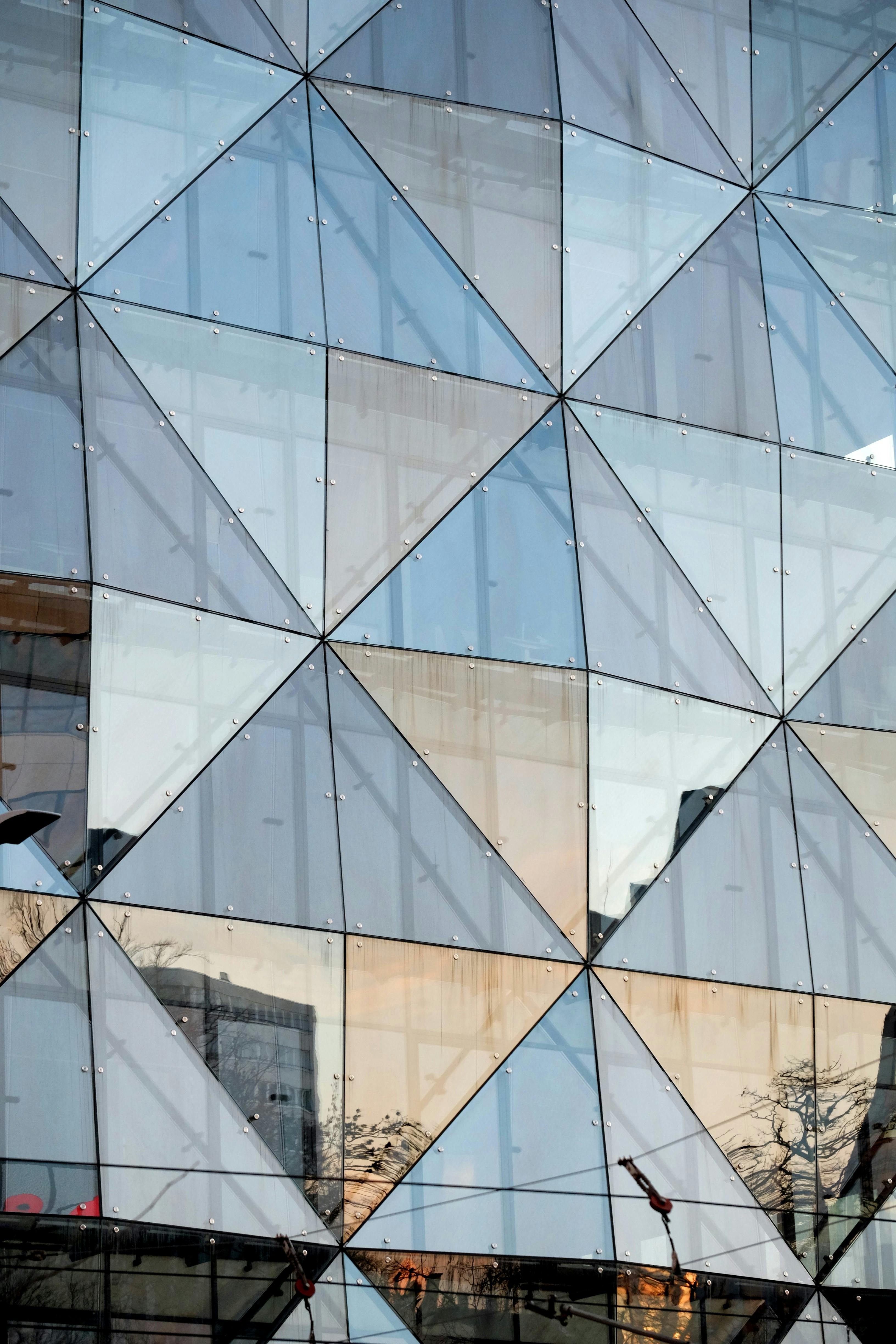 Gratis Fasad bangunan modern dengan desain kaca geometris yang mencerminkan cakrawala kota. Foto Stok