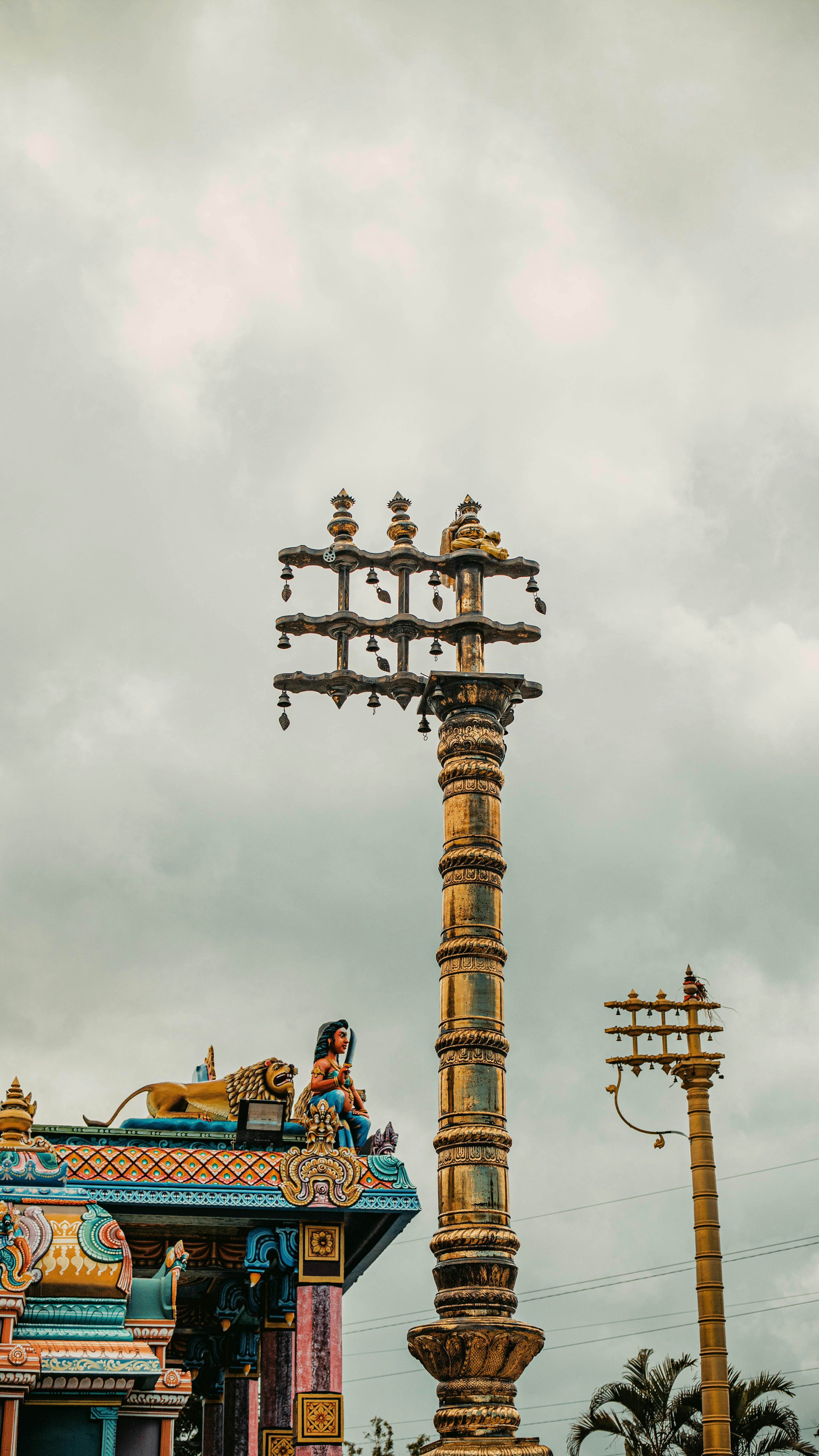 бесплатная Потрясающий вид на величественный индуистский храм и богато украшенную колонну на фоне облачного неба на острове Реюньон. Стоковое фото