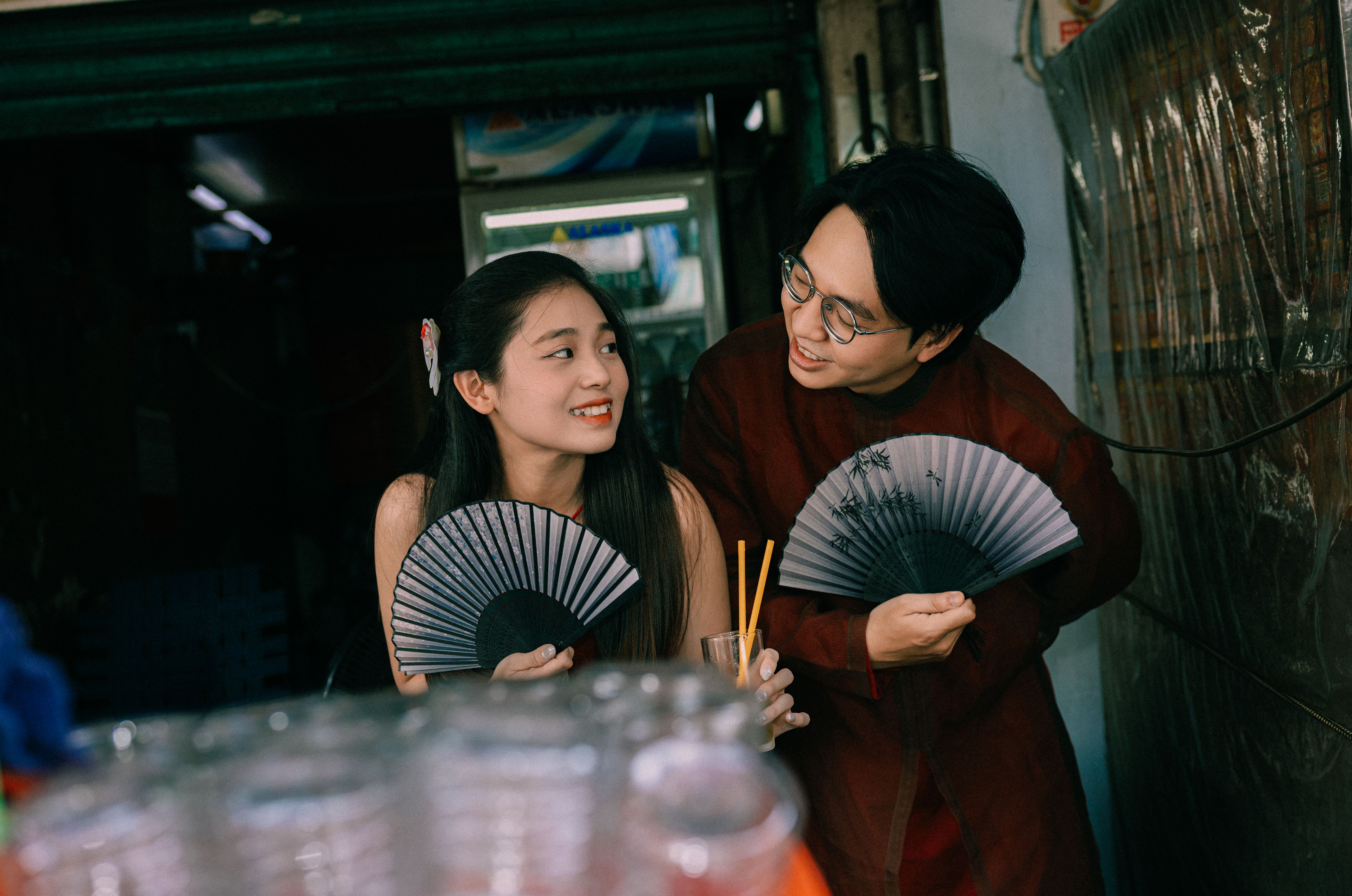 Friendly Conversation with Traditional Fans Indoors · Free Stock Photo