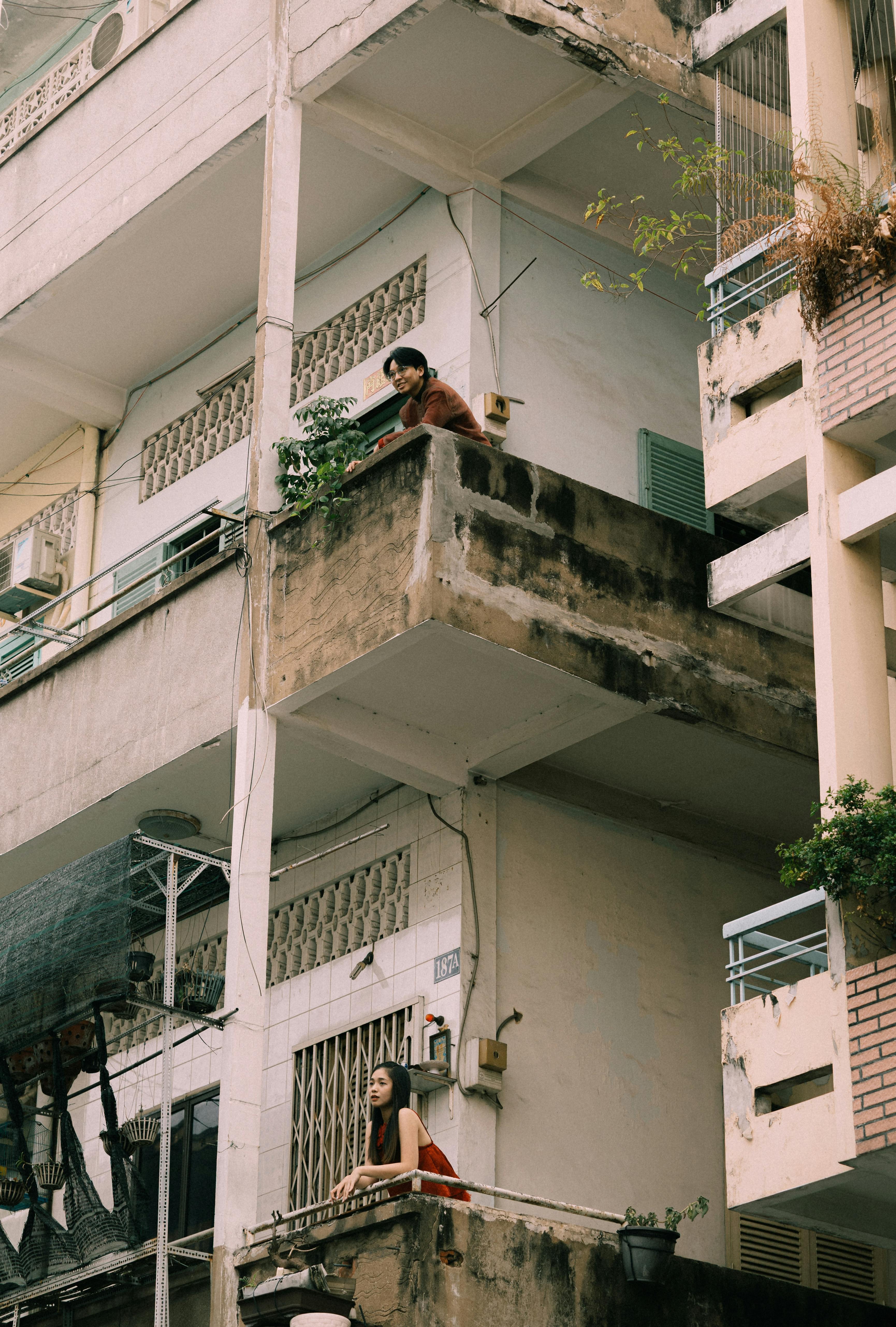 無料 都会の風景にあるアパートのバルコニーにいる2人の人物。日常生活を伝えています。 写真素材